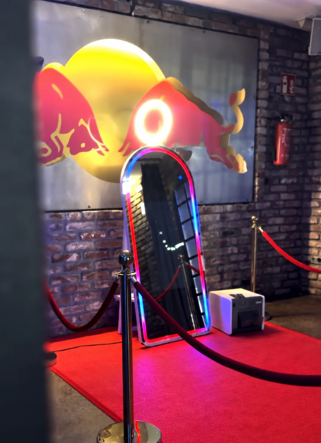 Fotospiegel mit farbiger Beleuchtung vor einer Wand mit Red-Bull-Logo